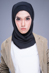 Beautiful Muslim female model in casual wear and hijab, urban lifestyle apparel for Muslim women isolated on grey background. Beauty and urban hijab fashion concept. Half length portrait.