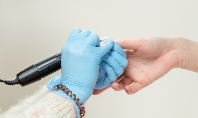 Manicure in a beauty salon. Manicurist scribbling fingernails with an electric nail drill