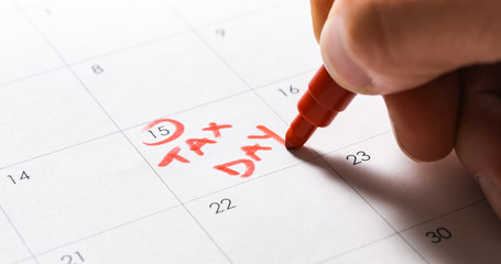 Circling April 15 and writing Tax Day in red on calendar.