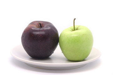 Green and red apple on a plate isolated on a white background.