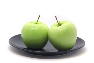 Green apples on a plate isolated on a white background.