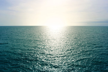 Atlantic ocean horizon line at sunset, with blue sea water with calm waves and yellow warm sun - evocative deep seascape wallpaper
