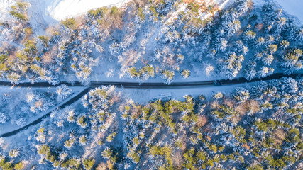 Aerial view of curvy road in snowy forest in Austrian mountains. Top view of road, winter landscape 