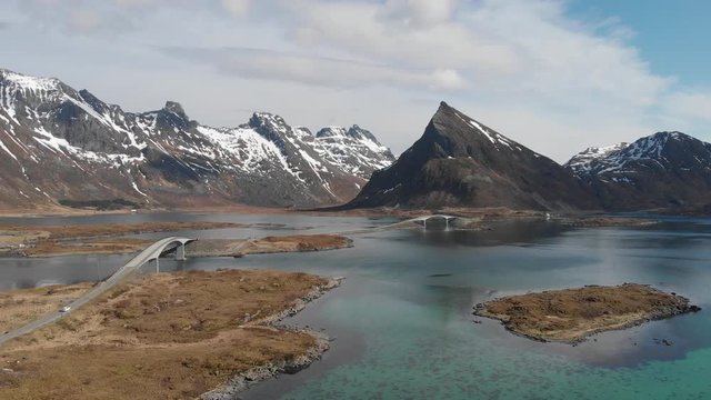 Car driving over iconic bridges at the Lofoten Islands in front of unbelievable cliffy rock formations