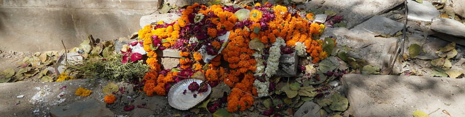 This is a picture of pollutants like decomposing flowers. A large pile of garbage, wet waste of flowers and paper plates. Bunch of withered flowers and Flower garlands thrown as trash.