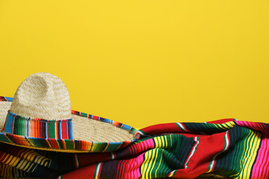 Mexican sombrero on a colorful serape blanket on a yellow background. Cinco de Mayo theme