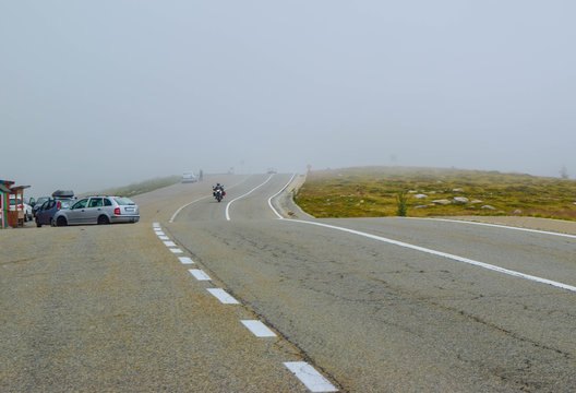 Motorcyclist and cars in fog on the Transalpina road DN67C. This is one of the most beautiful alpine routes in Romania and the highest mountain asphalt road in Romania and  Carpathians mountains.