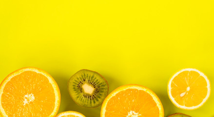 Fruit frame. Colorful fresh citrus fruits on a light green background. Orange, tangerine, lemon and kiwi are cut in half. Flat lay, top view, copy space.