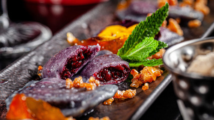 Ukrainian cuisine in the European style. Sweet dumplings with cherries, candied orange and edible flowers. Beautiful serving in the restaurant. background image, copy space text