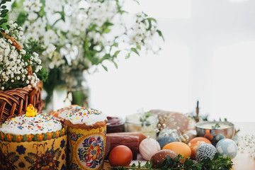 Easter brunch.  Easter modern eggs, easter bread, ham, beets, butter, cheese, sausages, green branches and flowers on rustic wooden table. Holiday preparation. Traditional Easter Food.