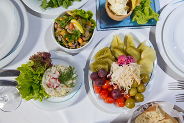 Set of a dish with spoon, fork and knife on white table.Table setting on white table . Served holiday table, cutlery, crockery, glasses, plate, fork. Salads and gums .