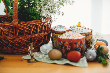 Easter cake, easter eggs natural dyed, candle, green branches and flowers on rustic wooden table with wicker basket. Traditional Easter Food for sanctify in church.