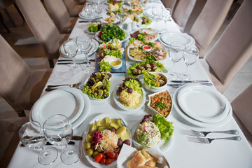 Salads and gums . Set of a dish with spoon, fork and knife on white table.Table setting on white table .