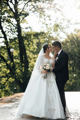 Loving wedding couple outdoor. Bride and groom. Wedding couple. Close up of a newlywed couple, a bride with a beautiful hair style and make up. Happy newlywed couple walking in the park.