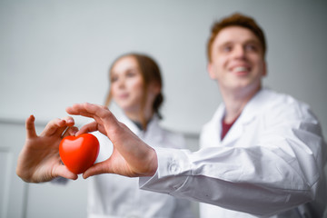 Close up photo Two cardiologist holding a red toy heart