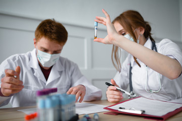 Attractive doctor and his assistant perform tests in a forensic laboratory