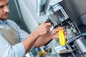 Coffee Passion. Young barista at coffee shop cleaning steamer concentrated close-up