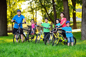 Young large family on bicycles in the Park against the background of greenery and trees.family Day