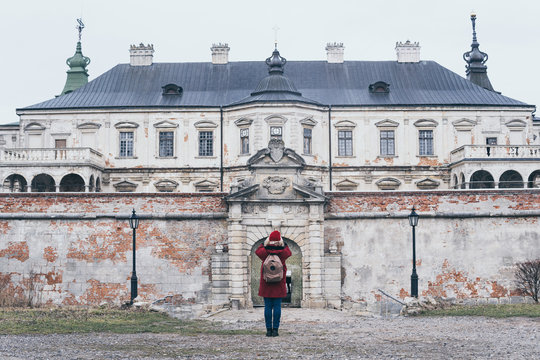 Pidhirtsi, Ukraine - December 2019: Woman in red coat taking picture of Pidhirtsi Castle in Lviv region