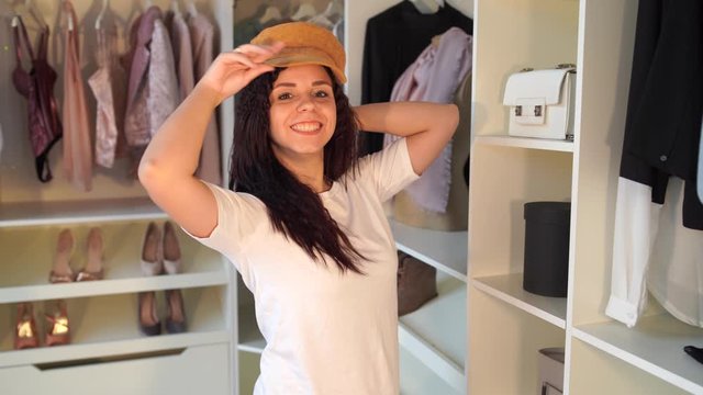 A woman tries on a hat in the dressing room. Female try on hat and looking in mirror. Happy yound woman dressing, young lady wearing funny hat. Happy shopping concept.
