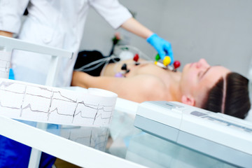 doctor with electrocardiogram equipment making cardiogram test to male patient in hospital clinic - obrazy, fototapety, plakaty