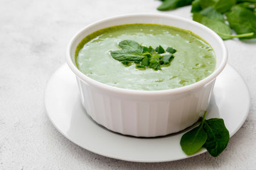 Creamy broccoli soup in a white bowl, spring healthy green creamy soup. Detox, dieting or clean eating food.