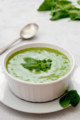 Creamy broccoli soup in a white bowl, spring healthy green creamy soup. Detox, dieting or clean eating food.
