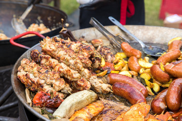 Kebabs of meat, sausages, potatoes in a rustic style fried in a large pan. The concept of fast food, street restaurants and fairs.