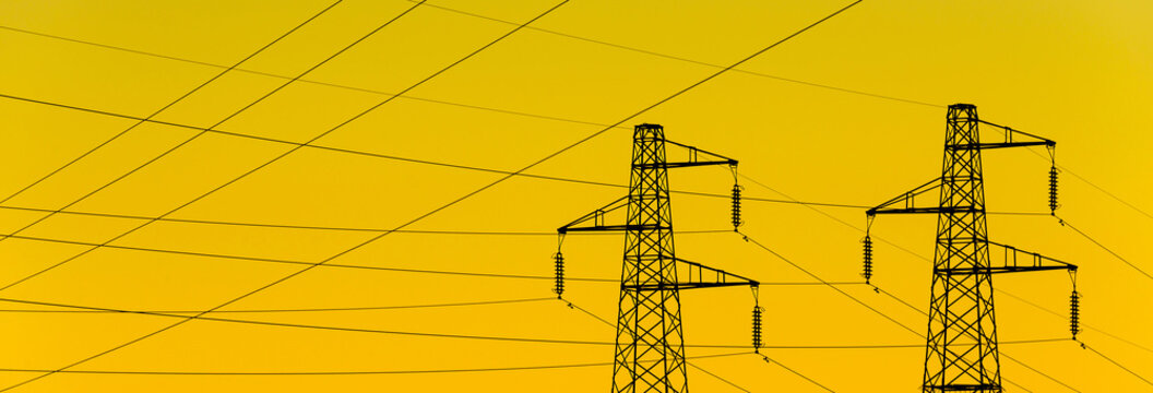 Electric power industry. Transmission towers or electricity pylons with golden sky background