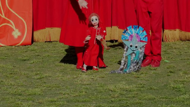 This video shows cute child and stars puppets dancing at an outdoor retro marionette theater show.