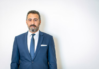 A bearded businessman, posing in a suit in front of the background
