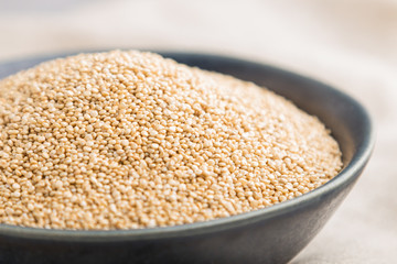 Blue ceramic bowl with raw white quinoa seeds on a gray concrete  background. Side view, selective focus.