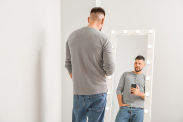 Fototapeta premium Handsome man taking selfie near mirror at home