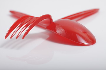 Red plastic cutlery on an isolated white background