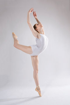 Young woman ballet dancer in white leotard in the studio.