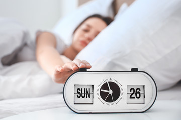 Morning of beautiful young woman turning off alarm clock in bedroom