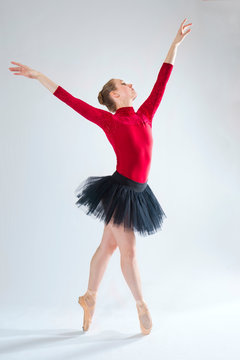 Young woman ballet dancer in red leotard and black tutu.