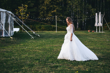 Beautiful young woman in a white wedding dress and black boots at sunset is photographed.