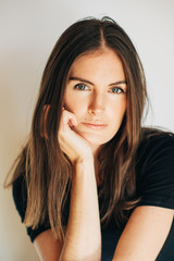 Close up portrait of beautiful young woman wearing black t-shirt, posing on white background