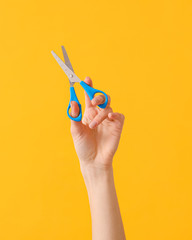 Hand with scissors on color background - obrazy, fototapety, plakaty