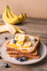 Tasty toasted bread with honey, butter and fruits on plate