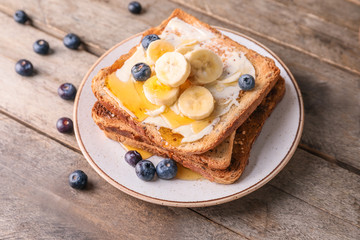 Tasty toasted bread with honey, butter and fruits on plate