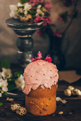 Traditional Russian Orthodox Easter pink bread kulich with apple blossom and colored eggs in rustic style background