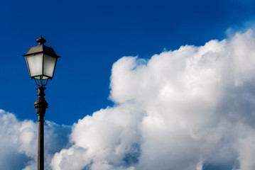 Fototapeta na wymiar Old fashioned street lamp against beautiful blue sky and white clouds (with copy space)