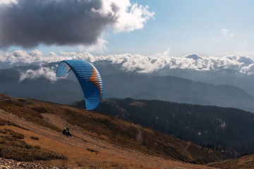Paraglider flying over the mountains on a bright sunny day. Paragliding sport concept. Copy space.
