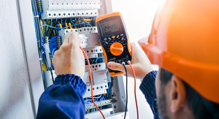 Electrician installing electric cable wires of fuse switch box. - obrazy, fototapety, plakaty