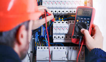 Electrician installing electric cable wires of fuse switch box.