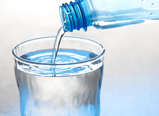 Water is pouring from a bottle into a glass Isolated on a white background