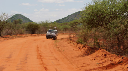 Obraz na płótnie Canvas Car with tourists and landscape of the African savanna and the mountain in the background in Kenya in Africa.