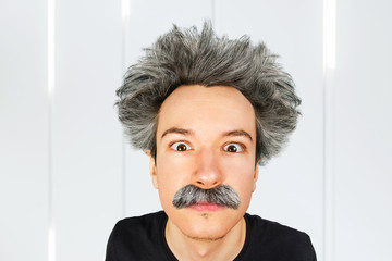 Portrait of jocular aging guy with grey long hair sticking his tongue out in Einstein manner. - obrazy, fototapety, plakaty